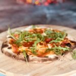 circa events sharing pizza pizza on wooden board with fresh rocket