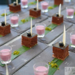 circa events dessert hazlenut parfait on a slate with banana leaf and shot glass with pink raspberry coulis dip