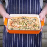 circa events sharing dishes lasagne held by chef outside wearing a blue and white chefs apron