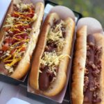 circa dirty dogs street food evening food option, three loaded hot dogs with meat, cheese and sauces