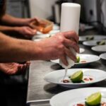 chef preparing starter dishes drizzling on a plate with sauce bottle
