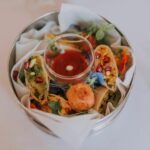 circa events canapes handmade vegetable spring rolls with chilli dip in a metal indian tin on a white tablecloth