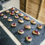 circa events canape outdoors, salt baked baby potato with beetroot and edible viola flowers on a slate