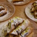 homemade cannoli with ricotta and pistachio on wooden boards
