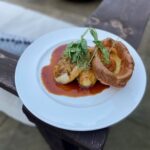 circa roast chicken with jus and yorkshire pudding on a white plate with a wooden background