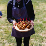 circa canape held by staff on sunny day on wooden board with heart skewers