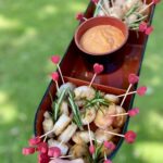 prawns with dipping sauce on heart skewers in an asian bowl on the grass